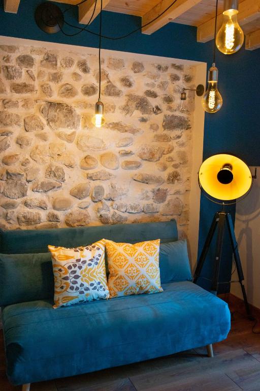 a blue couch in a room with a stone wall at Appartement atypique au coeur des Alpes in Barraux