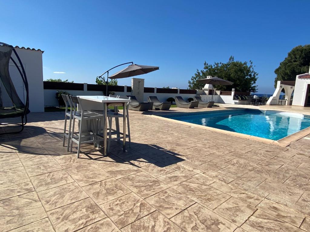 un patio con mesa y sillas junto a una piscina en The Belvedere Villa Latchi, en Lachi