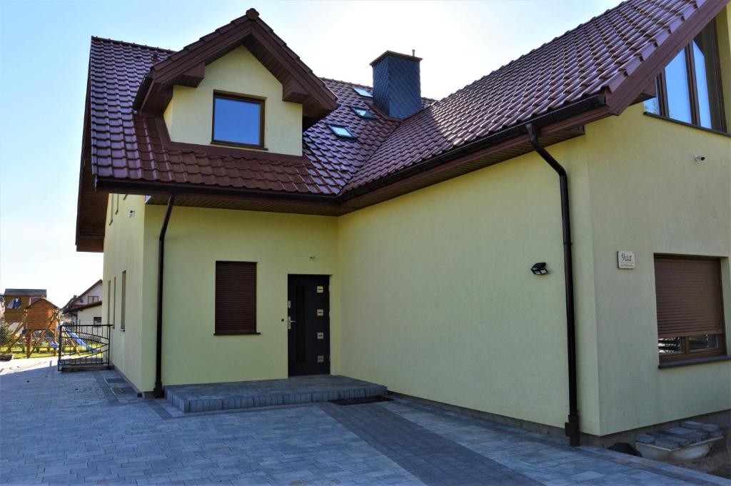 una casa amarilla con techo marrón en Pokoje U IGORA, en Mikołajki