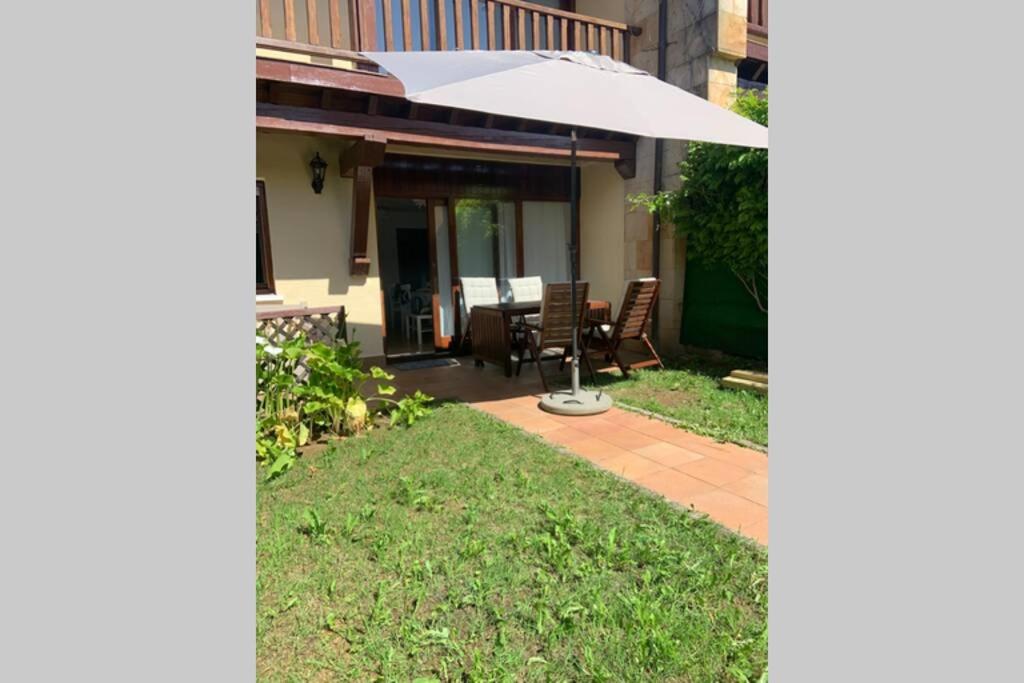 eine Terrasse mit einem Tisch und einem Sonnenschirm in der Unterkunft Apartamento en el Paseo de Manuel Noriega, Nº 9, con jardín privado, Wifi, en Comillas in Comillas
