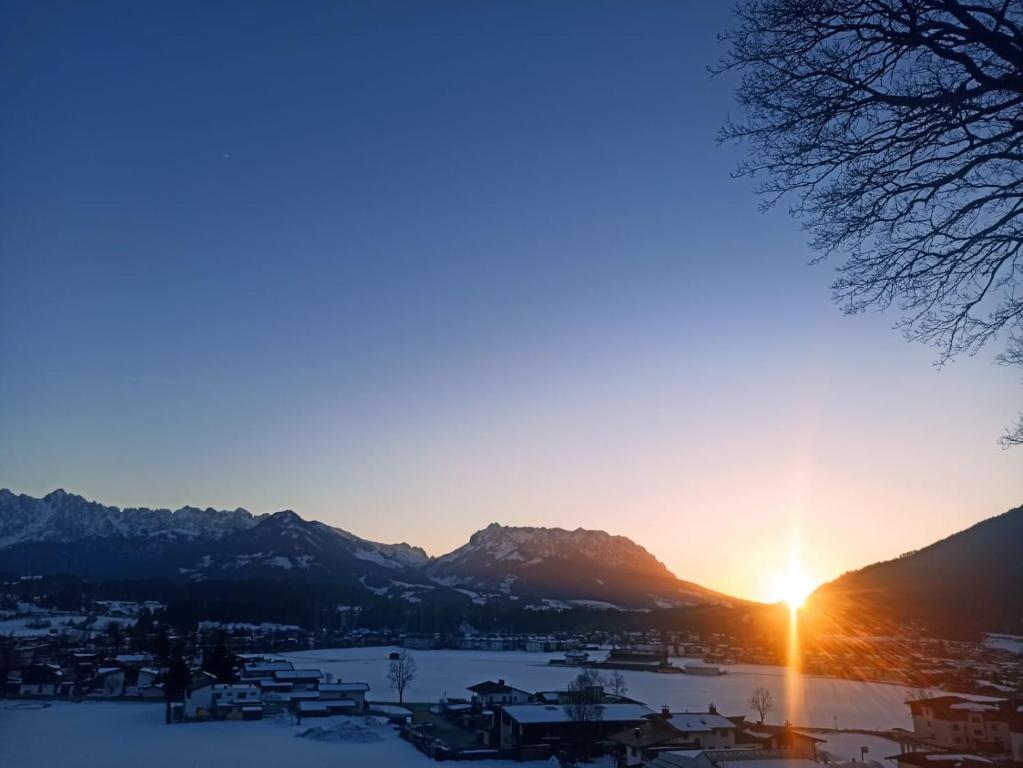 una puesta de sol sobre una ciudad con montañas en el fondo en Haus Sonnenwinkl, en Kössen