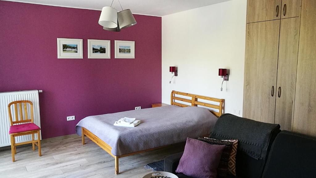 um quarto com uma cama e uma parede roxa em Apartament Parkowy em Nałęczów