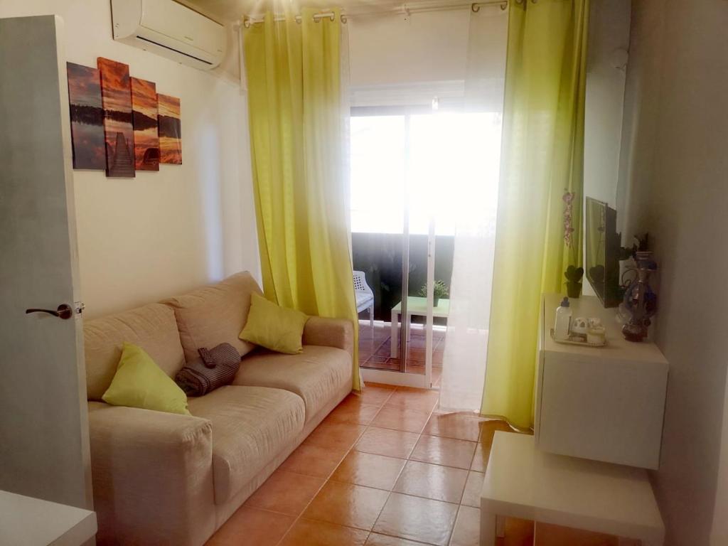 sala de estar con sofá y cortinas amarillas en Bonito Apartamento, en San Pedro del Pinatar
