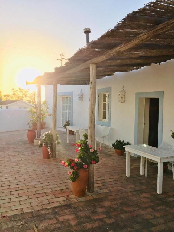 a patio with tables and potted plants in front of a building at Casa Largo do Poço Guesthouse in Alvor