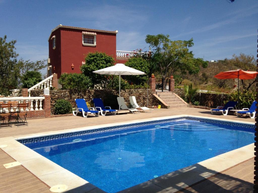 una piscina con sillas y sombrillas junto a un edificio en Casa Buena Vista, en Vélez-Málaga