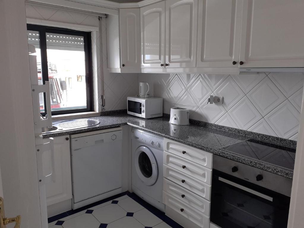 a white kitchen with a washer and a microwave at Clube Meia Praia in Lagos