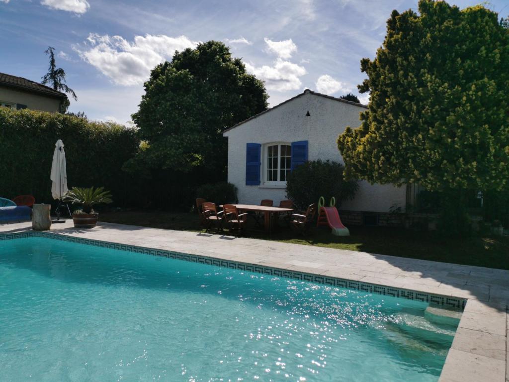 a swimming pool with a table and a house at LA PARENTHESE in Manduel