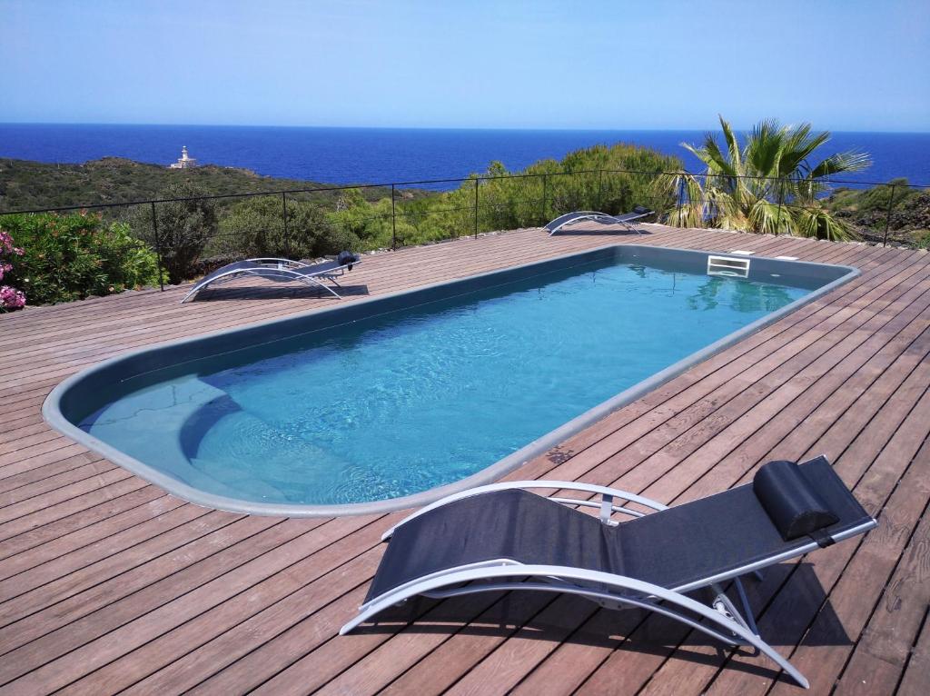 a swimming pool on top of a wooden deck with a chair at Agriturismo La Cala Cottone in Pantelleria