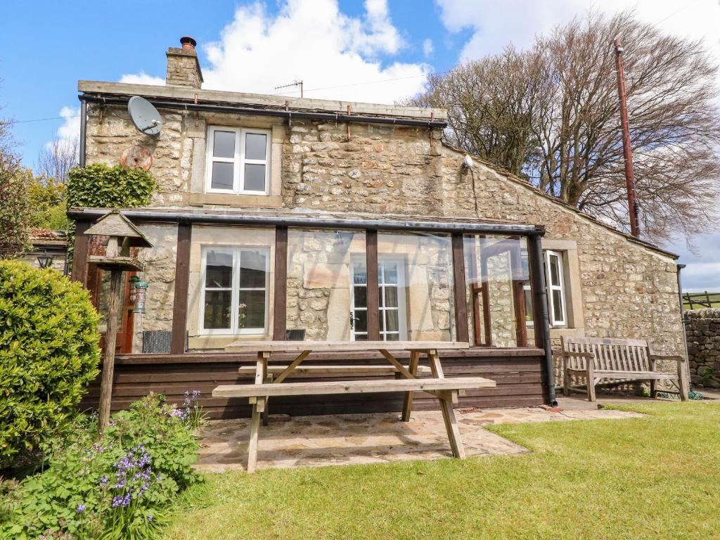 a stone cottage with a picnic bench in front of it at Sandywood in Skipton