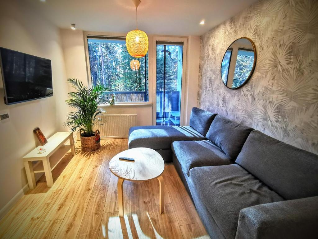 una sala de estar con un sofá y una mesa en Apartament Okna na Park, en Polanica-Zdrój