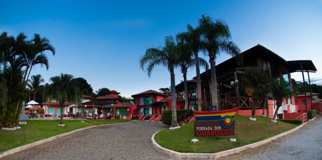a resort with palm trees and a sign in the road at Pousada dos Guardiões in Búzios