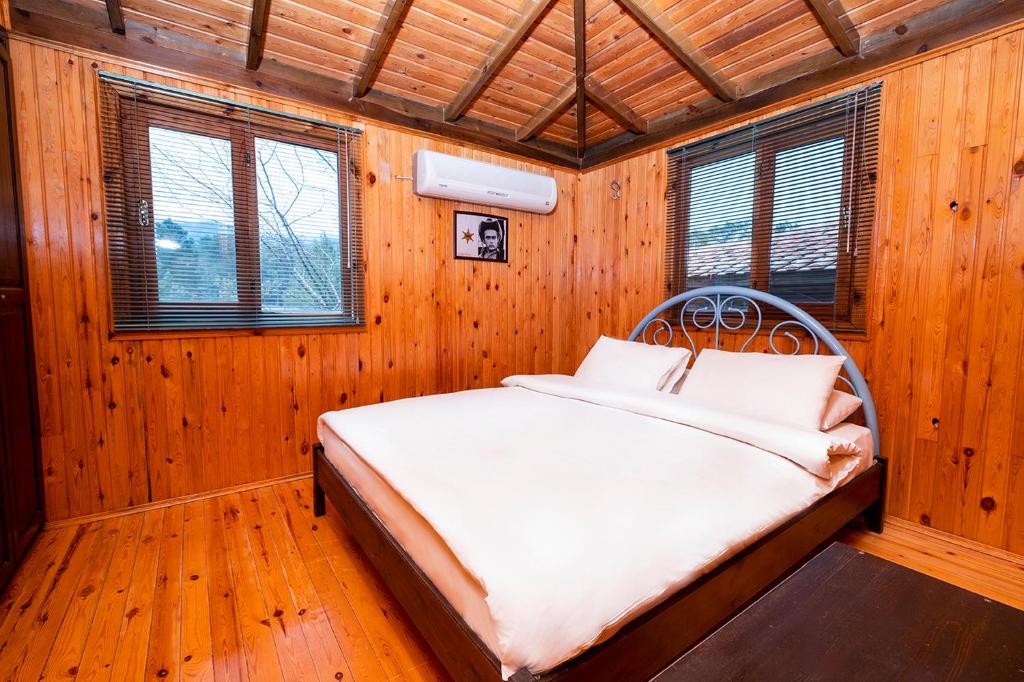 Ce lit se trouve dans un dortoir doté de murs en bois et de fenêtres. dans l'établissement Fifties Corner, à Olympos