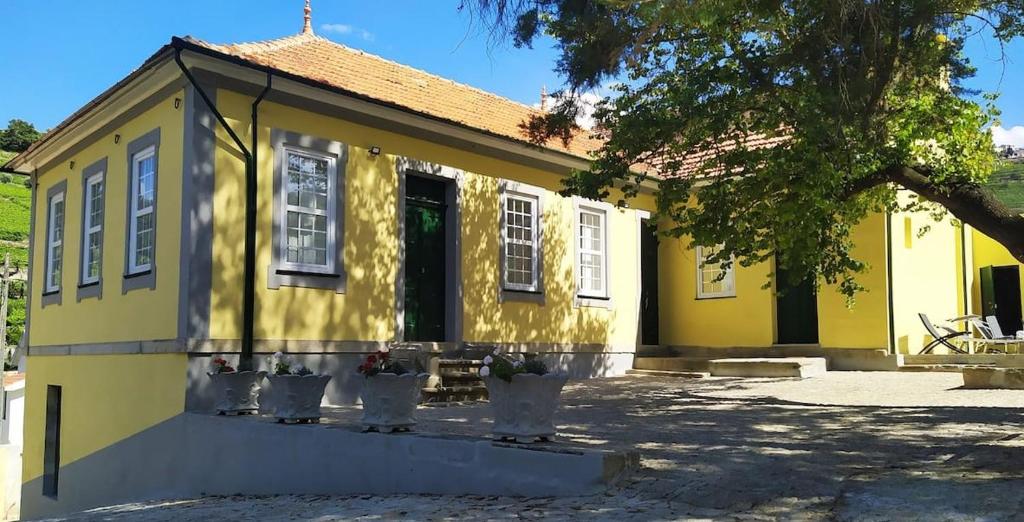 une maison jaune avec des fenêtres blanches et un arbre dans l'établissement Casa de São Roque - Lamego, à Cambres