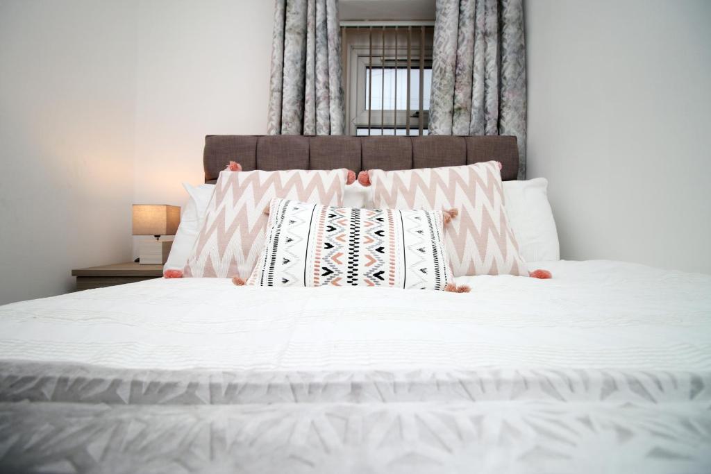 a white bed with two pillows on top of it at Stay in the Heart of Swansea- TV in Every Bedroom! in Swansea