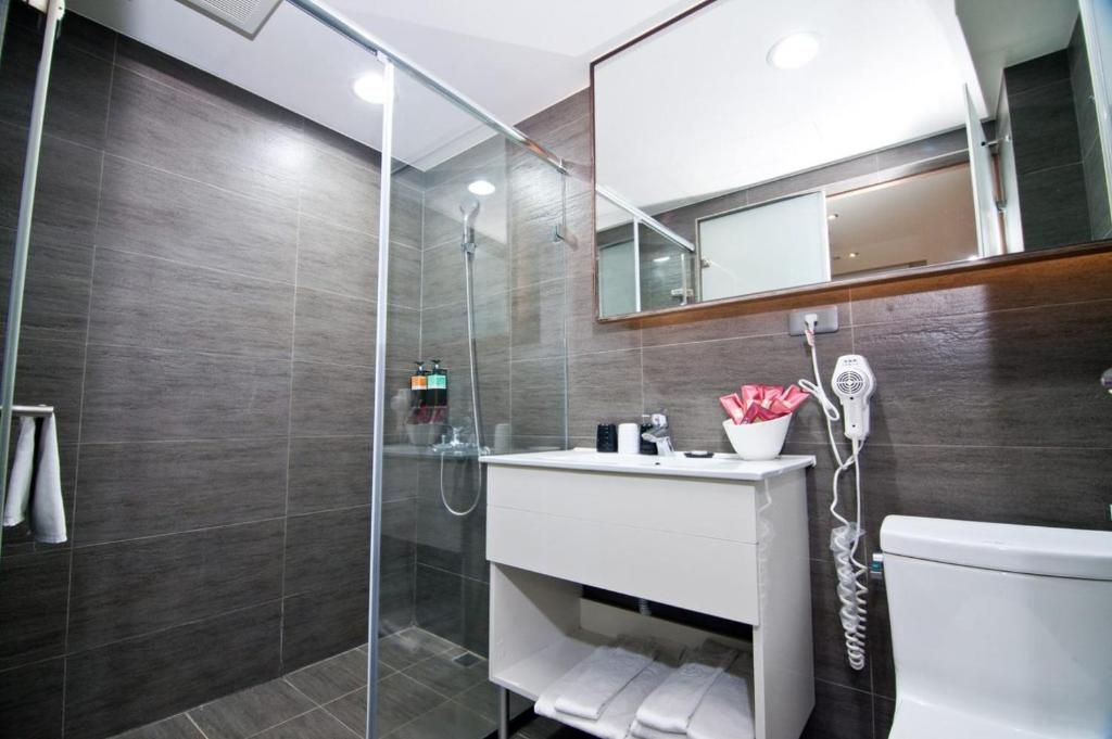 a bathroom with a shower and a toilet and a sink at Talmud Hotel Taichung in Taichung