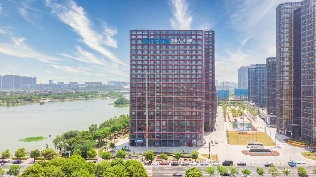 南京市にあるJinling Funhome Hotel Nanjing Jiulong Lake - Nanjing South Railway Stationの川の横の高層ビルの空中