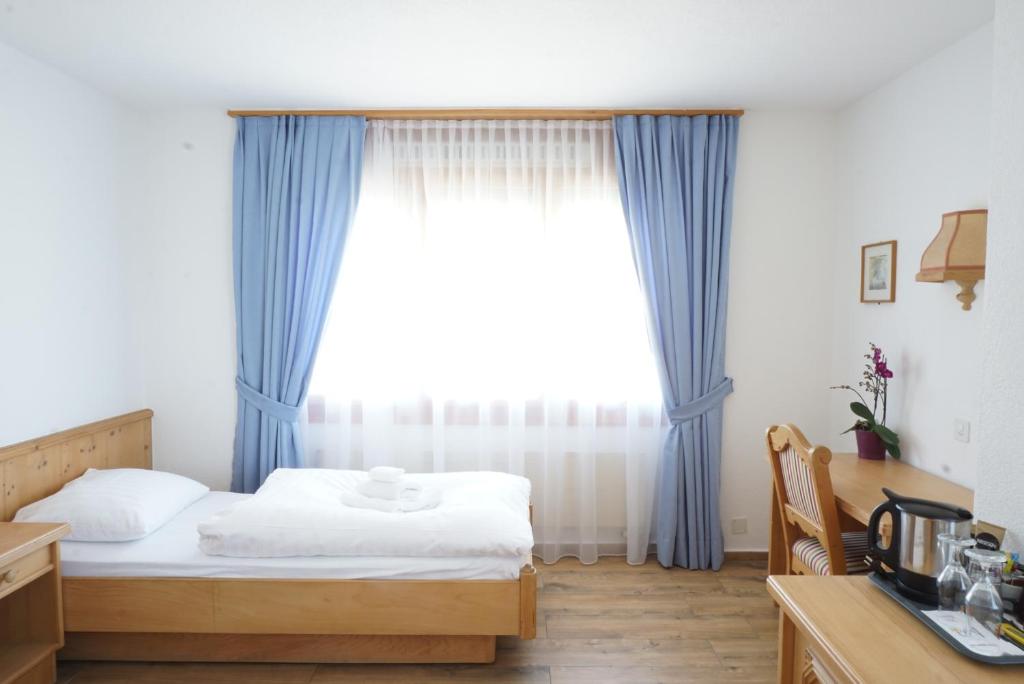 a bedroom with a bed and a window with blue curtains at Hotel Sternen in Aarau