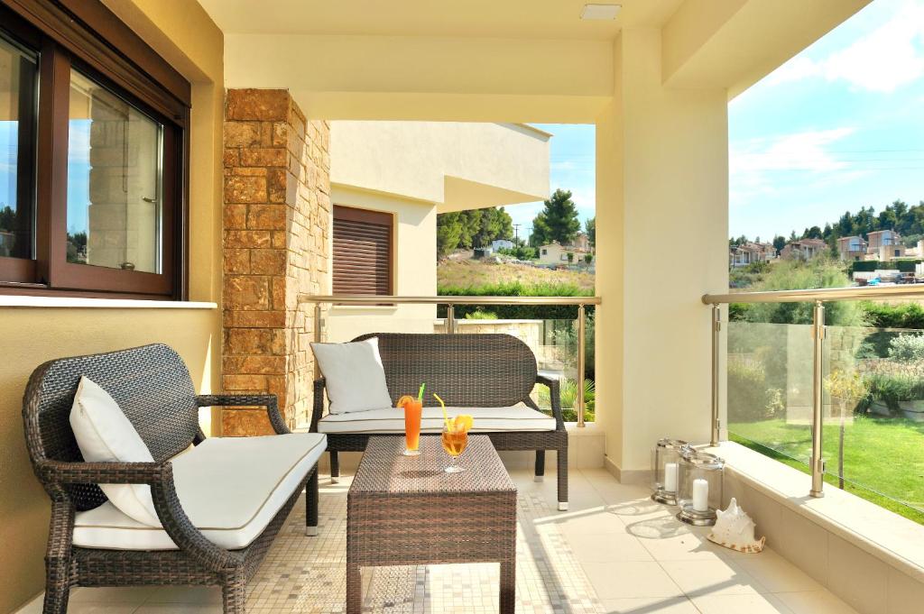 a patio with two chairs and a table on a balcony at Sani Polyastron Hotel & Spa in Sani Beach