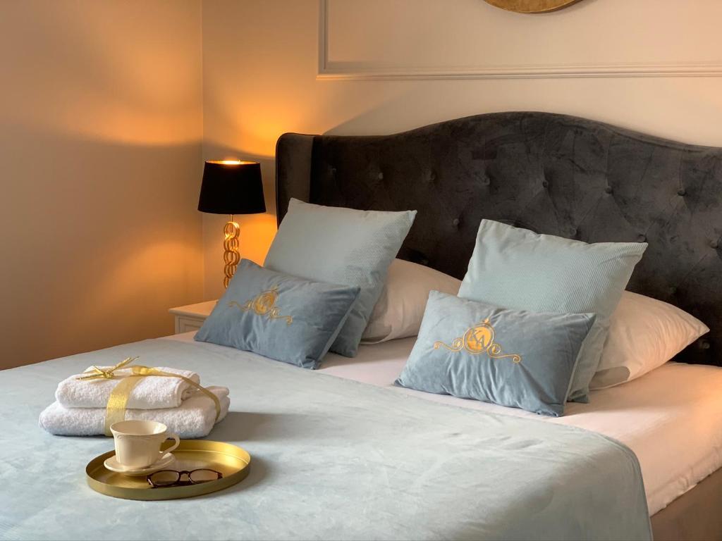 łóżko z niebieskimi poduszkami i złotą tacą w obiekcie Apartamenty Kamienica Arte 3 w Ustce