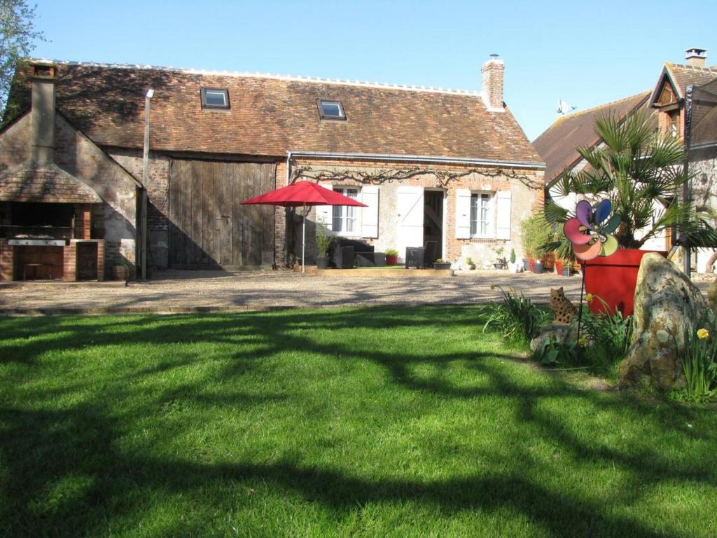una casa con un gran patio de césped con una sombrilla roja en Gîte Saint-Nicolas-des-Motets, 3 pièces, 4 personnes - FR-1-381-145 en Saint-Nicolas-des-Motets