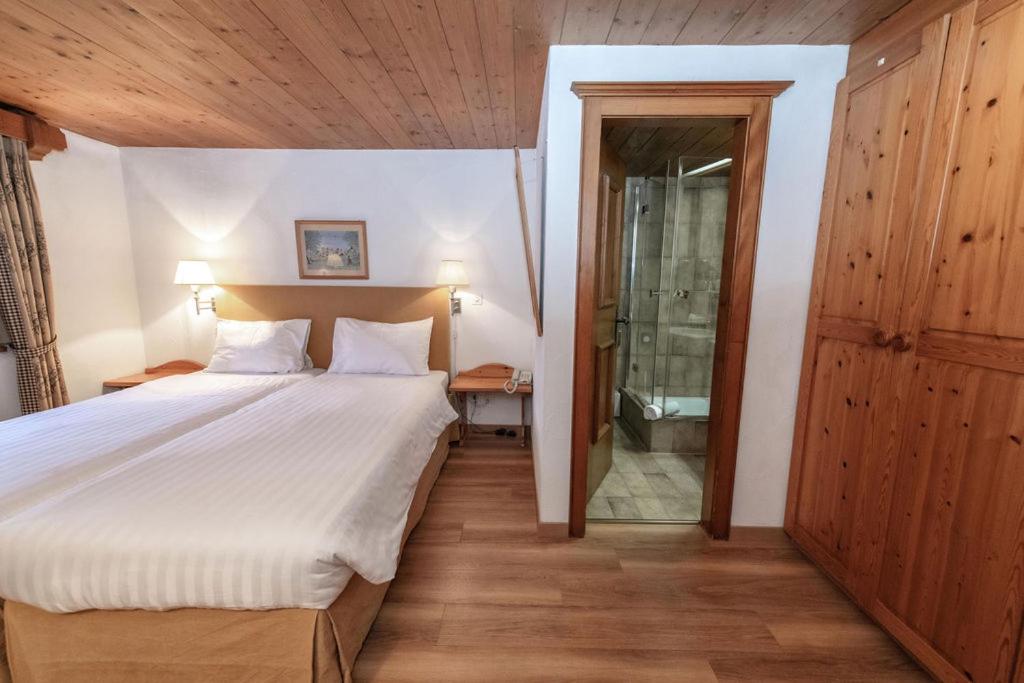 a bedroom with a bed and a walk in shower at Hotel Steinbock in Klosters