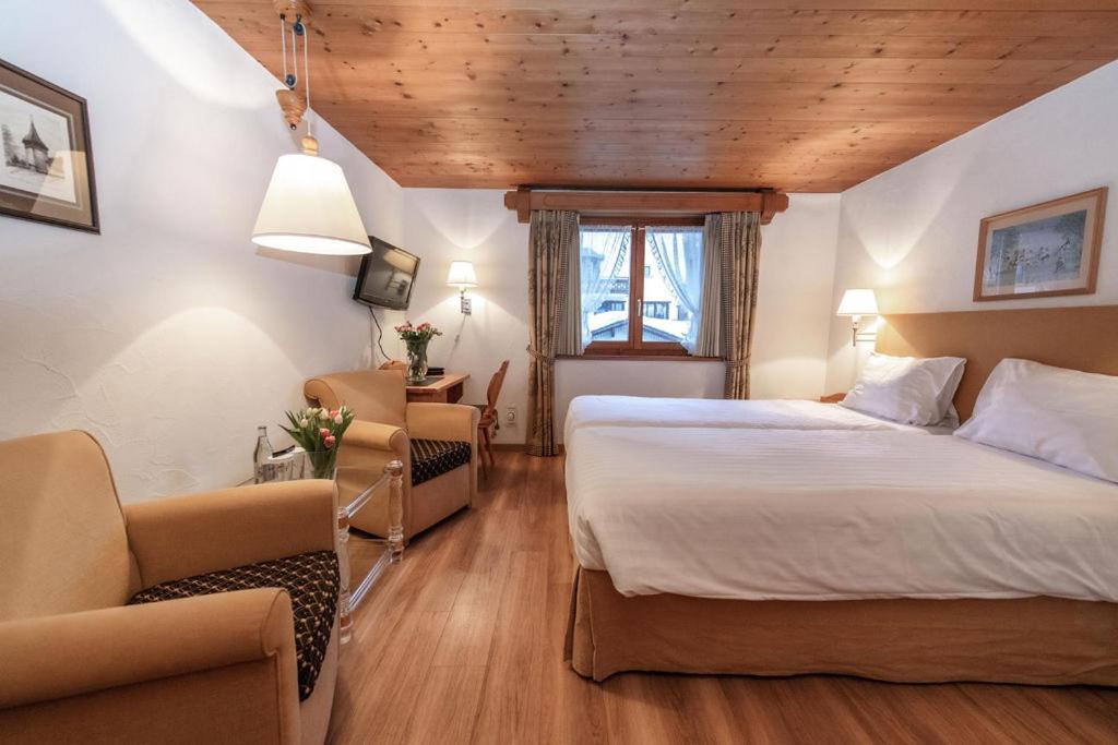 a hotel room with a bed and a chair at Hotel Steinbock in Klosters