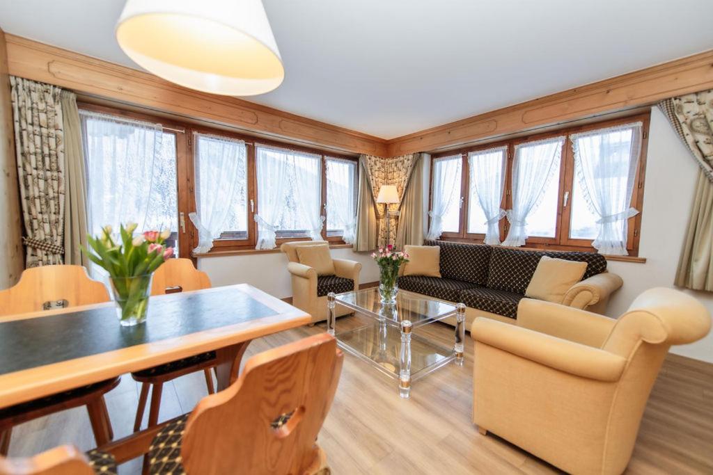 a living room with a table and chairs and windows at Hotel Steinbock in Klosters