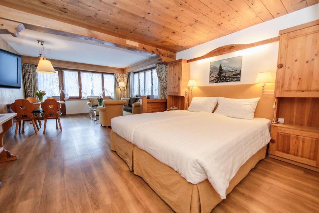 a bedroom with a large bed and a living room at Hotel Steinbock in Klosters