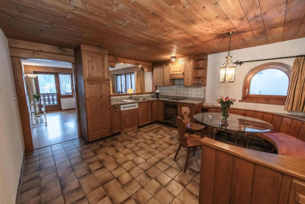 a kitchen with wooden cabinets and a table in it at Hotel Steinbock in Klosters
