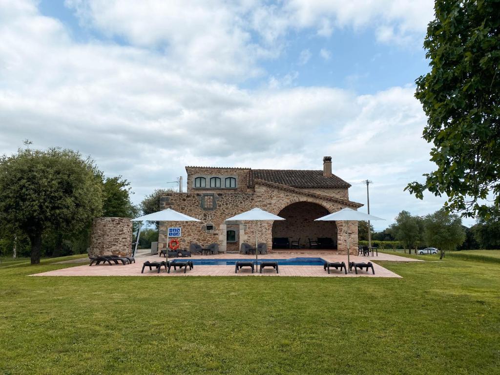 a building with tables and chairs in a park at Mas Trobat in Juià