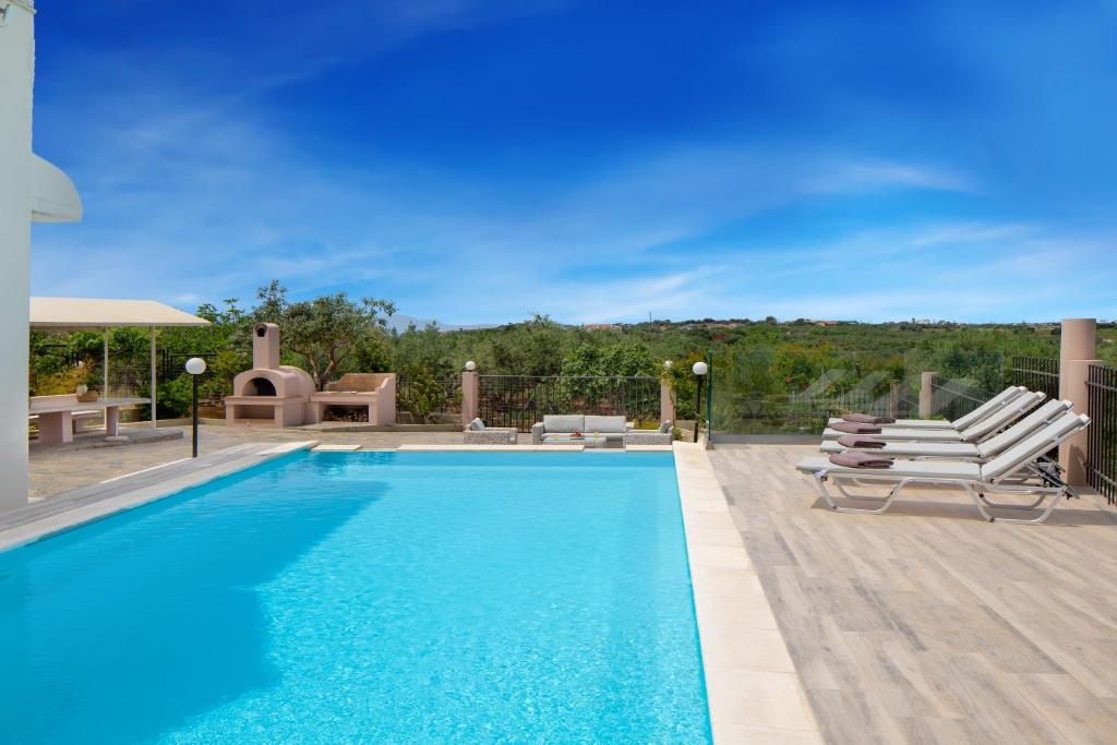 una piscina con 2 tumbonas y una piscina en Villa Elihrisos, en Chorafakia