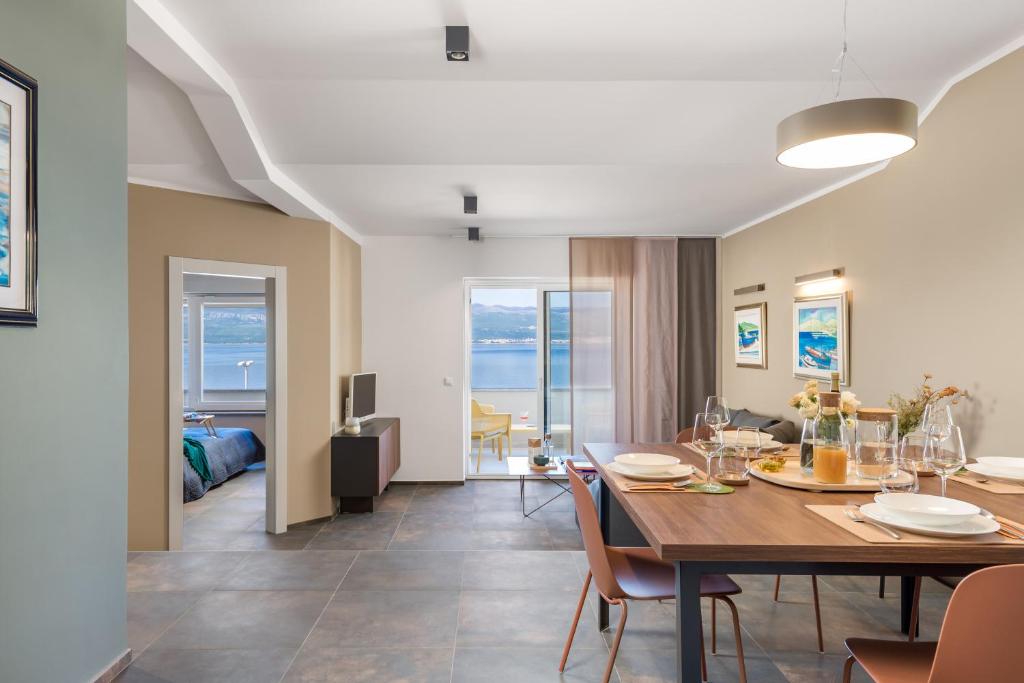 a dining room and living room with a table and chairs at Apartmani Heni in Vrbnik