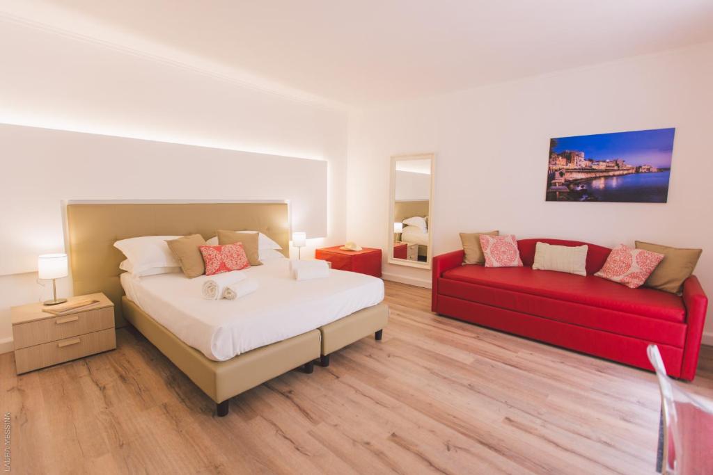 sypialnia z łóżkiem i czerwoną kanapą w obiekcie Dimore delle Zagare Ortigia w Syrakuzach