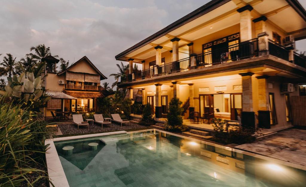 a villa with a swimming pool in front of a house at Ubud Shanti Rice Field House By Supala in Ubud