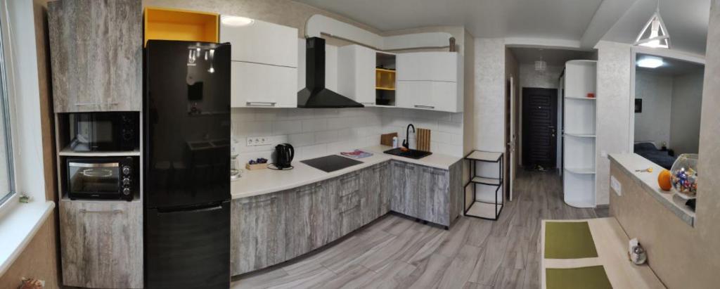 uma cozinha com um frigorífico preto e armários brancos em Апартаменты в ЖК " 30я Жемчужина KADORR" em Liski