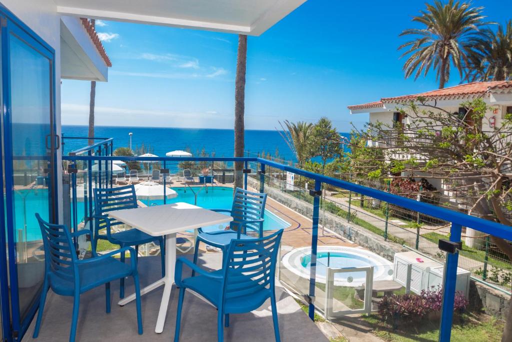 einen Balkon mit einem Tisch, Stühlen und Meerblick in der Unterkunft Alsol Los Caribes 1 in Playa del Ingles