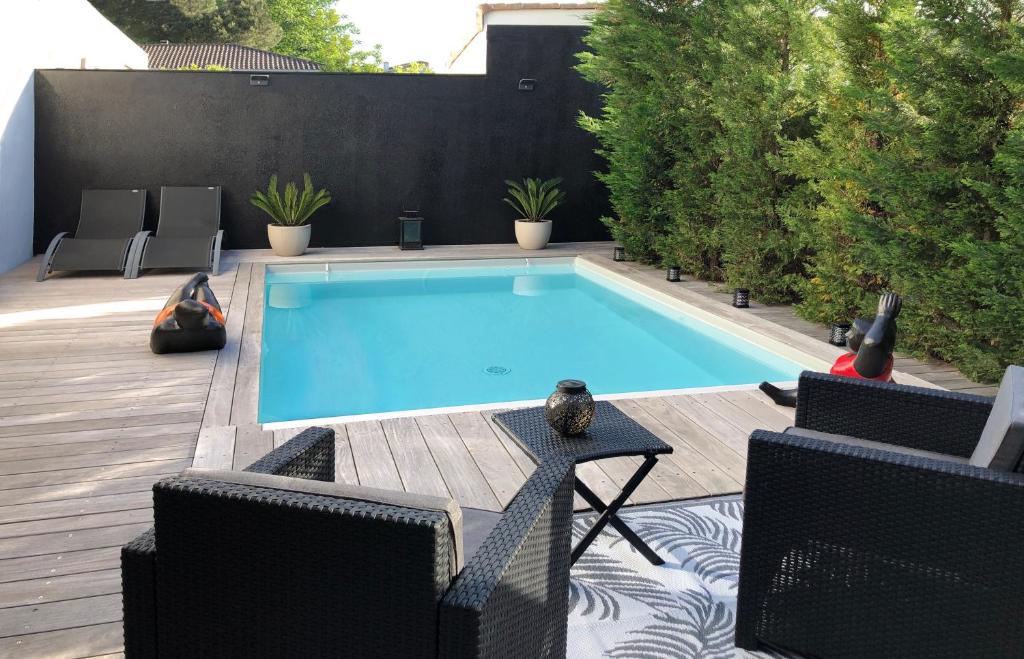 una piscina en un patio trasero con 2 sillas y una mesa en La Dolce Villa - Maison 100m2 avec piscine chauffée de mi mai à mi oct en fonction du temps et température à Bordeaux Caudéran en Burdeos