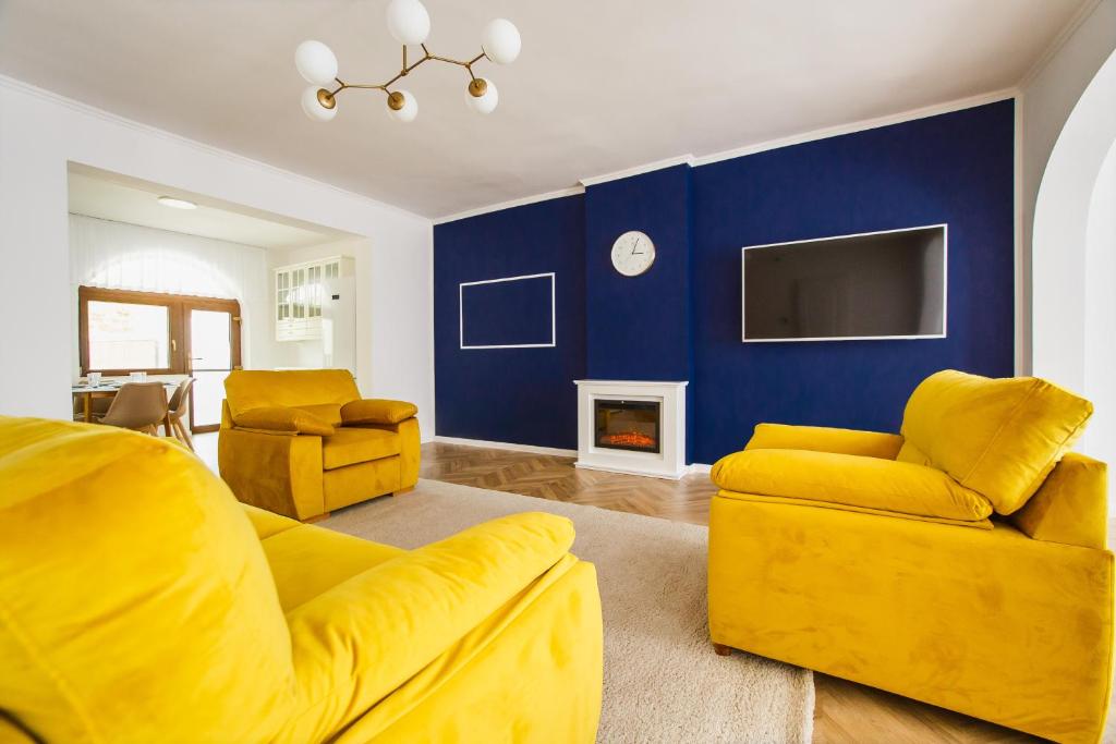 a living room with yellow furniture and a blue wall at Rya Residence Oradea in Oradea