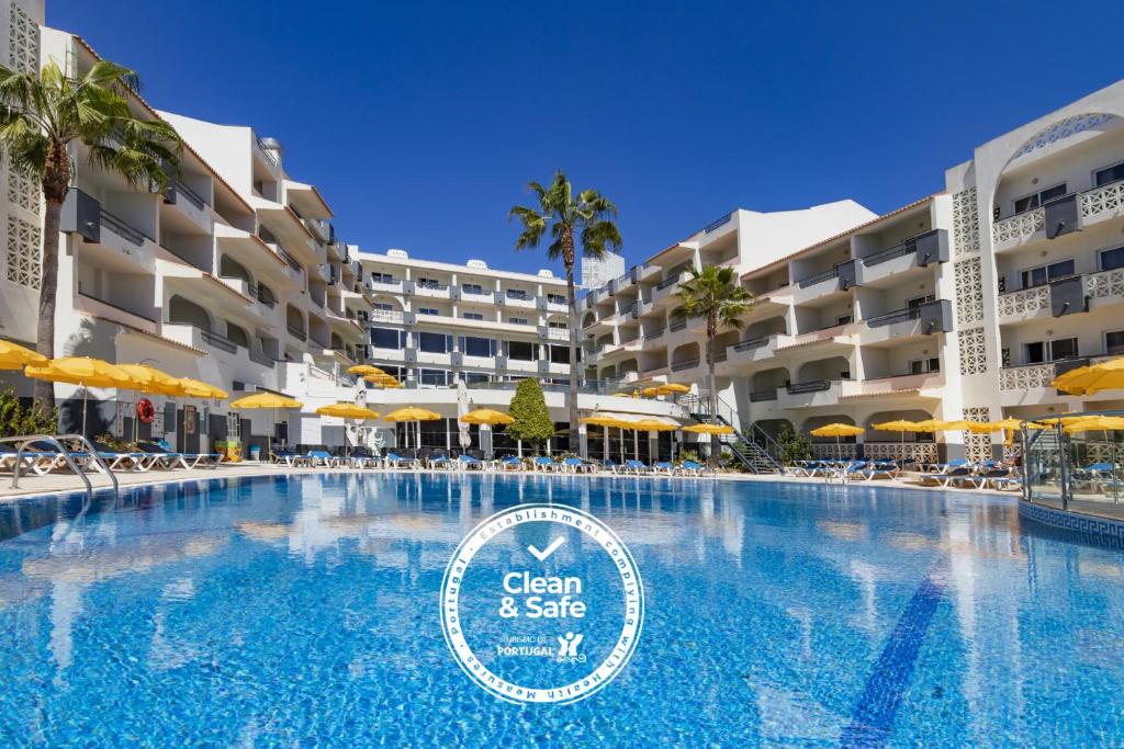 a swimming pool with chairs and umbrellas at a resort at Luna Miramar Club in Albufeira