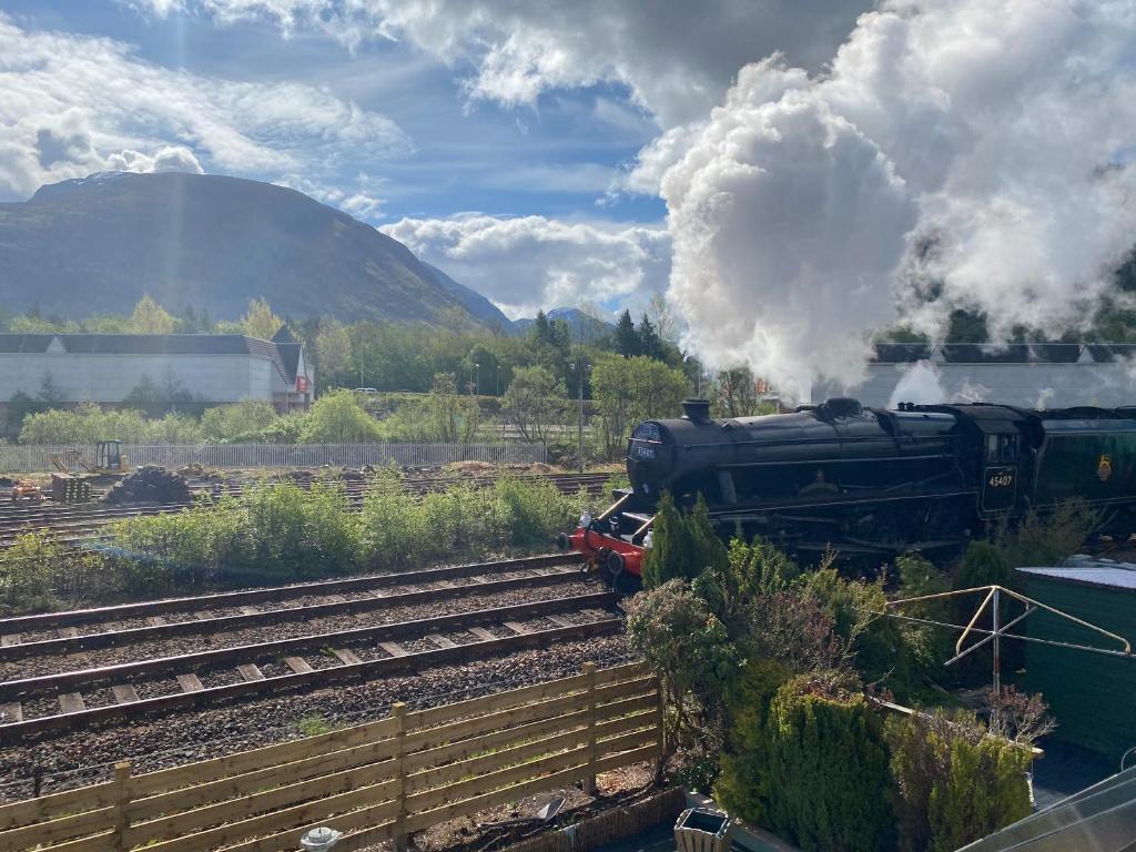 un tren de vapor está viajando por las vías en Braemar House, en Fort William