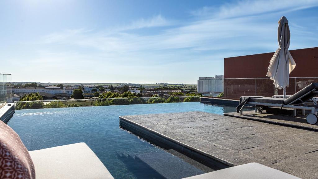 uma piscina com um guarda-sol num edifício em Vitoria Stone Hotel em Évora