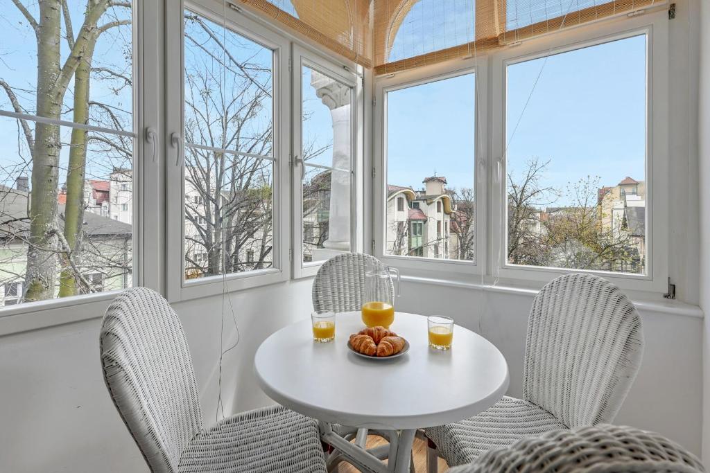 uma mesa branca e cadeiras num quarto com janelas em Blue Mandarin Apartments III Haffnera em Sopot