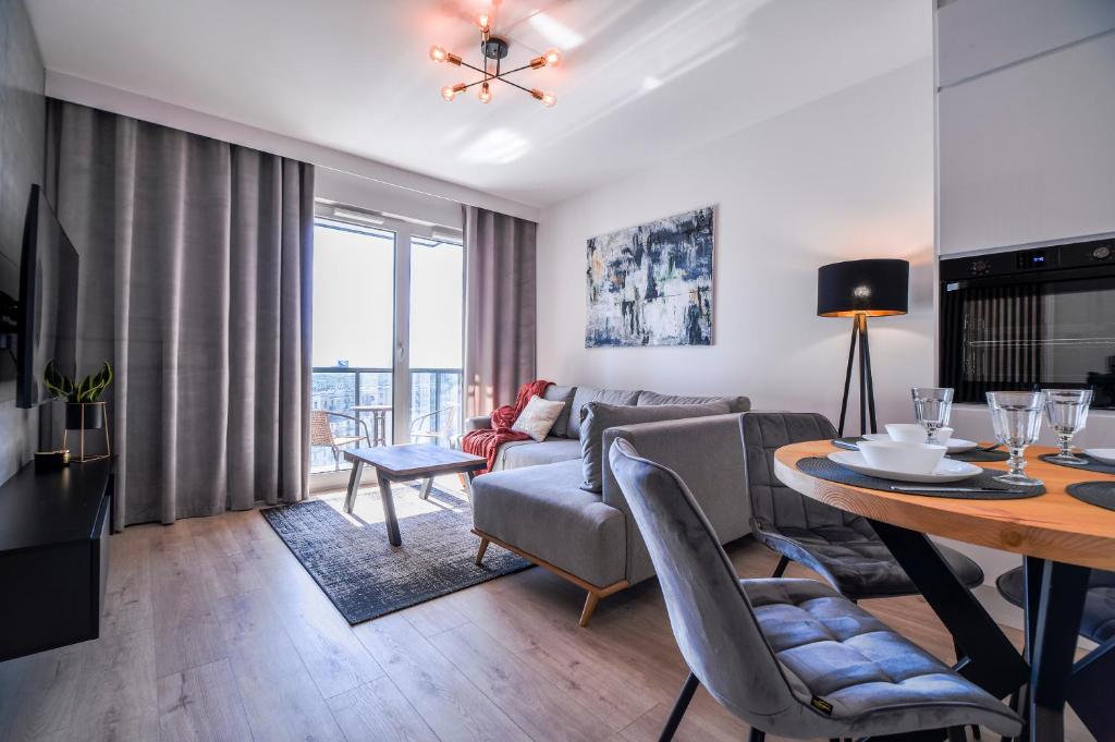 a living room with a dining room table and a couch at CITYSTAY Nowa Letnica Gdansk Apartment in Gdańsk