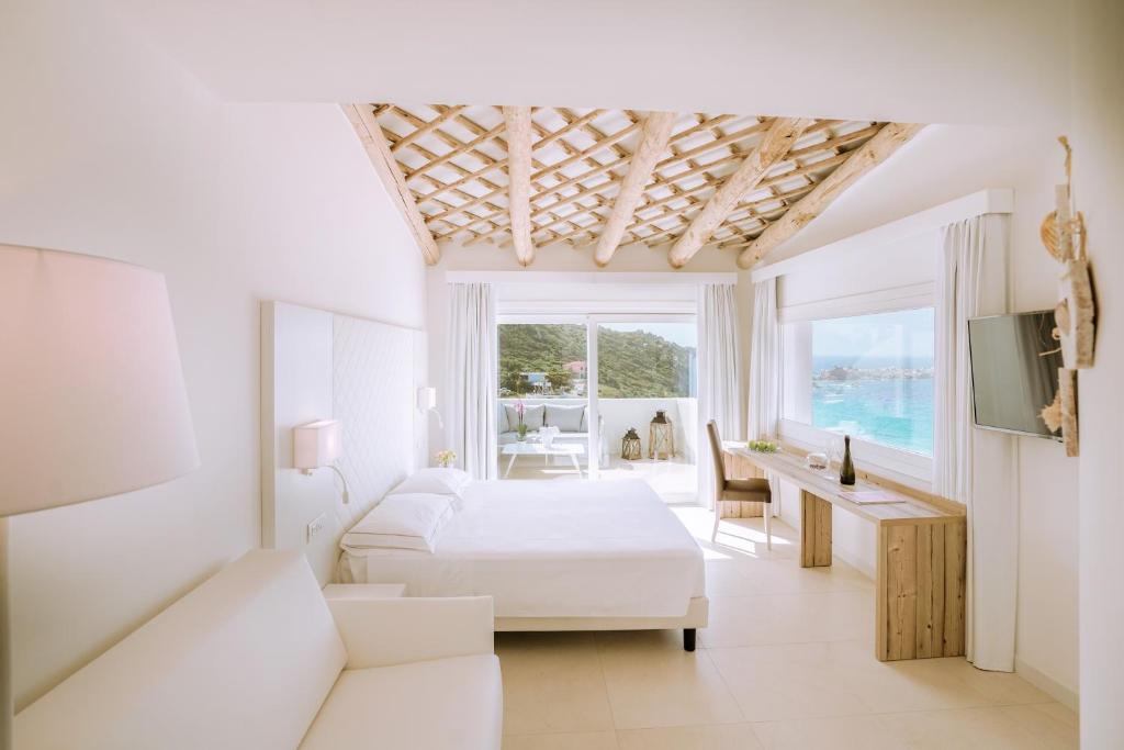 a white bedroom with a bed and a desk and a television at Hotel Moresco in Santa Teresa Gallura