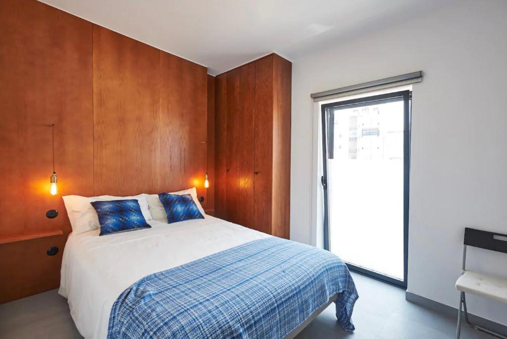 a bedroom with a bed and a large window at Pedra Branca Apartments in Ericeira