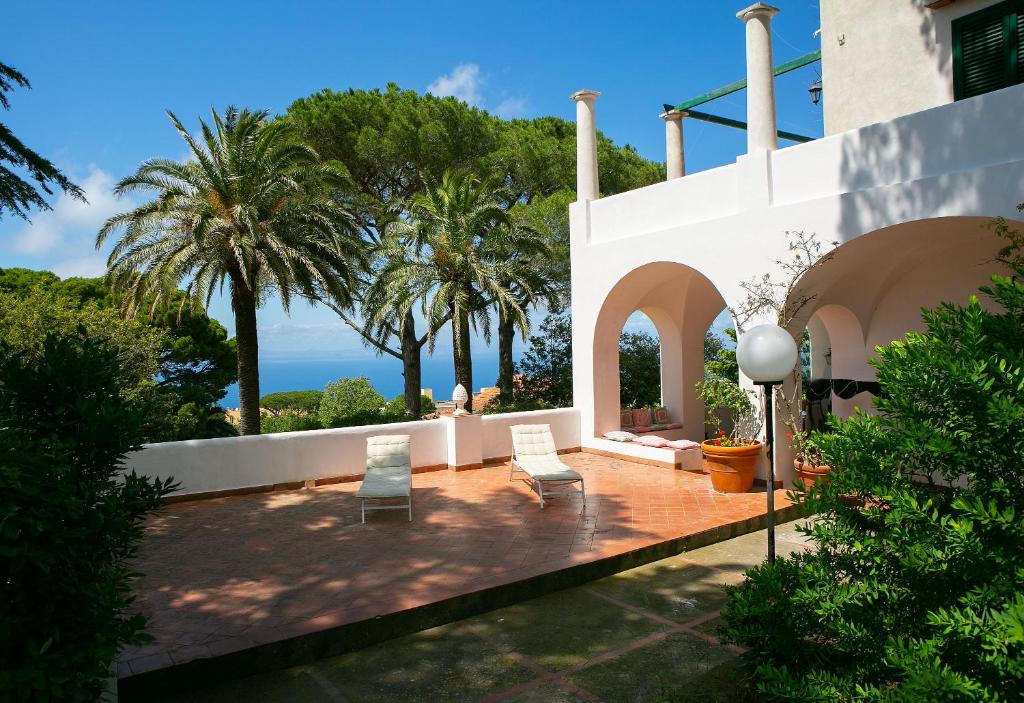 a patio with two chairs and palm trees at casa con vista panoramica in Anacapri