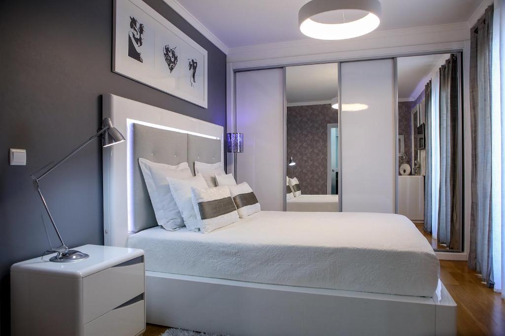 Schlafzimmer mit einem weißen Bett und einem Spiegel in der Unterkunft Apartamento Boutique Ana Lúcia in Santa Cruz