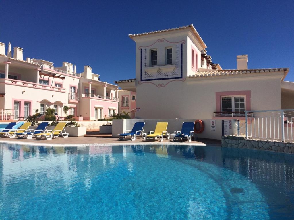 a large swimming pool in front of a house at Modern Two Bedroom Poolside Townhouse in Budens