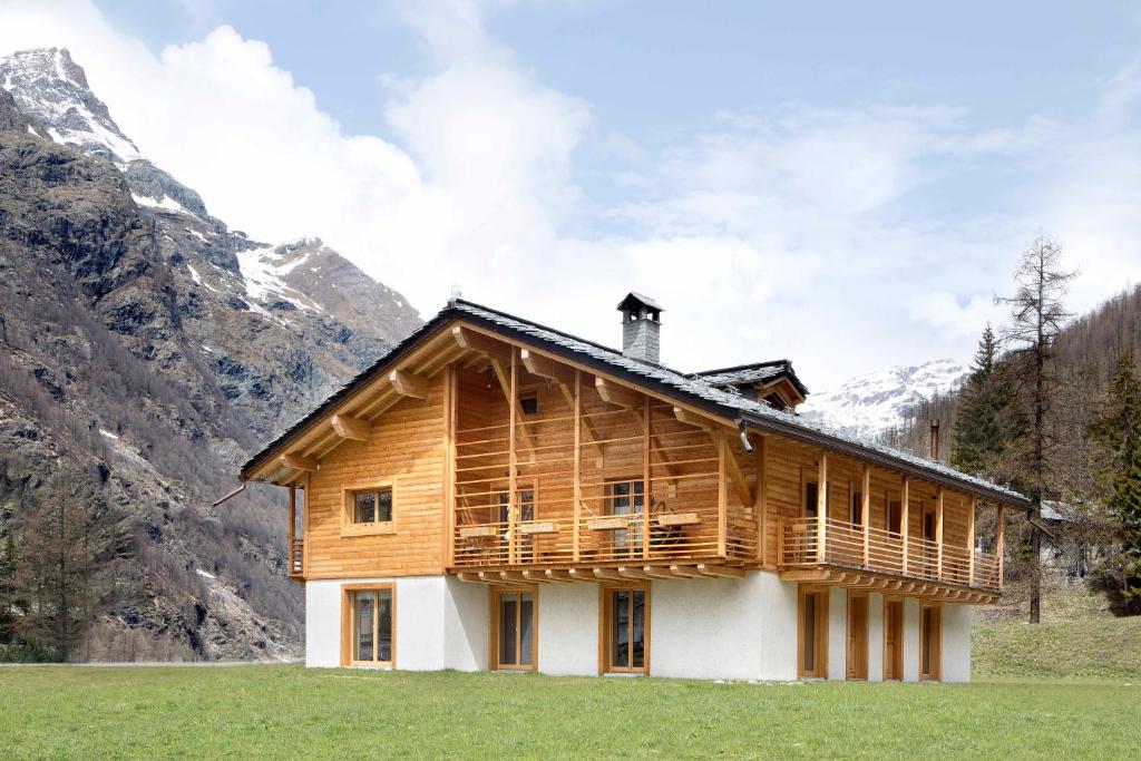 a wooden house in a field with mountains in the background at Bed & Breakfast Alchemilla in Gressoney-la-Trinité