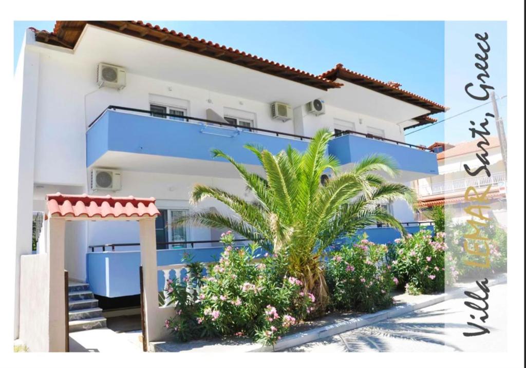 a blue and white building with palm trees and plants at Villa Lemar in Sarti